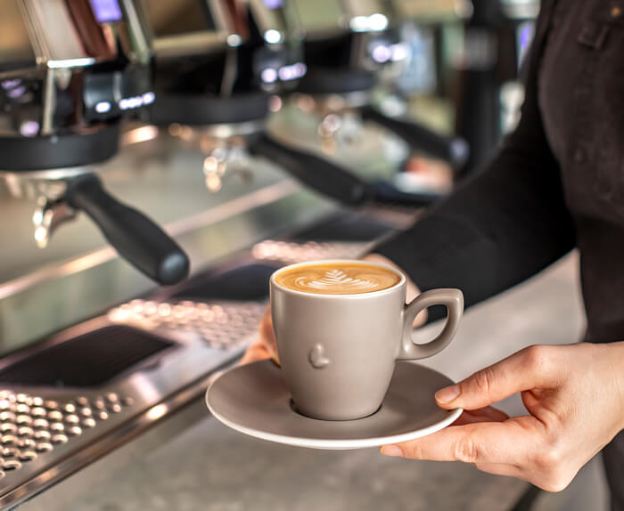 black-cappuccino Barista übergibt Cappuccino mit Latte Art
