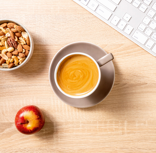 Tastatur, Nüsse, Kaffee und Apfel am Arbeitsplatz