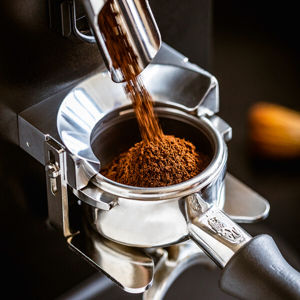 Kaffeemehl wird in aus der Kaffeemühe in den Siebträger gemahlen