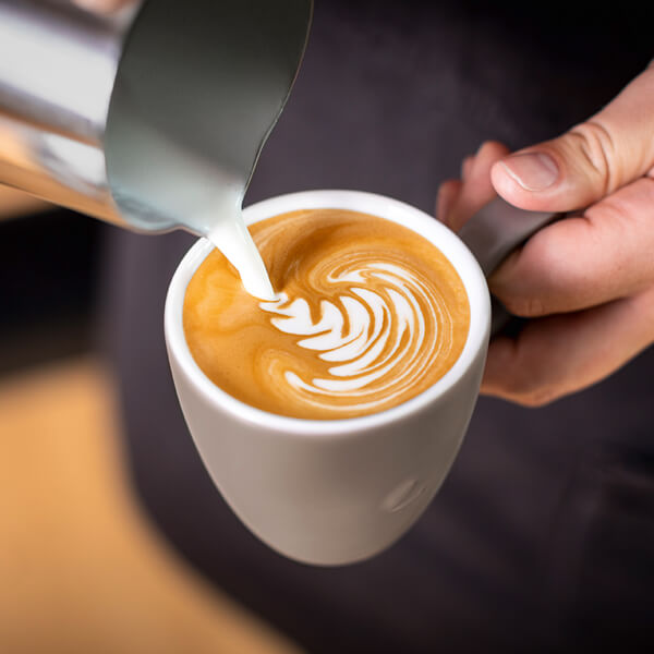 Barista erstellt Cappuccino mit Latte Art