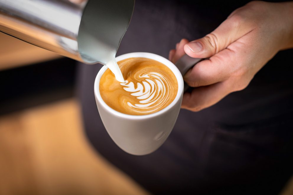 Latte Art in einen Cappuccino gießen