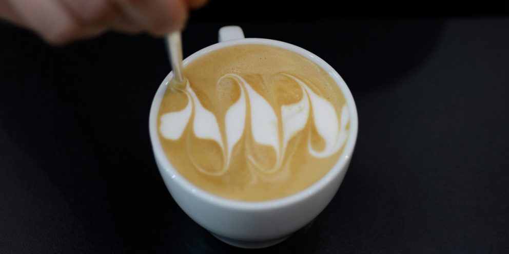 Person zeichnet mit einem Latte Pen ein Motiv in einen Cappuccino