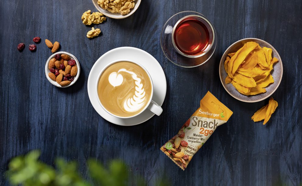 Kaffee mit Latte Art, Snack2go und Schale mit Nüsse und Früchten