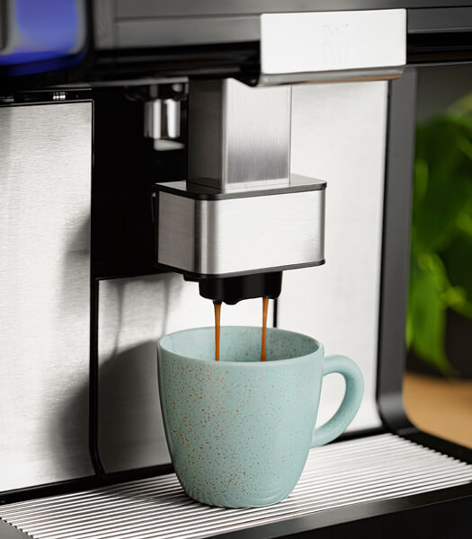 Kaffee läuft aus einem Kaffeeautomat in eine Tasse