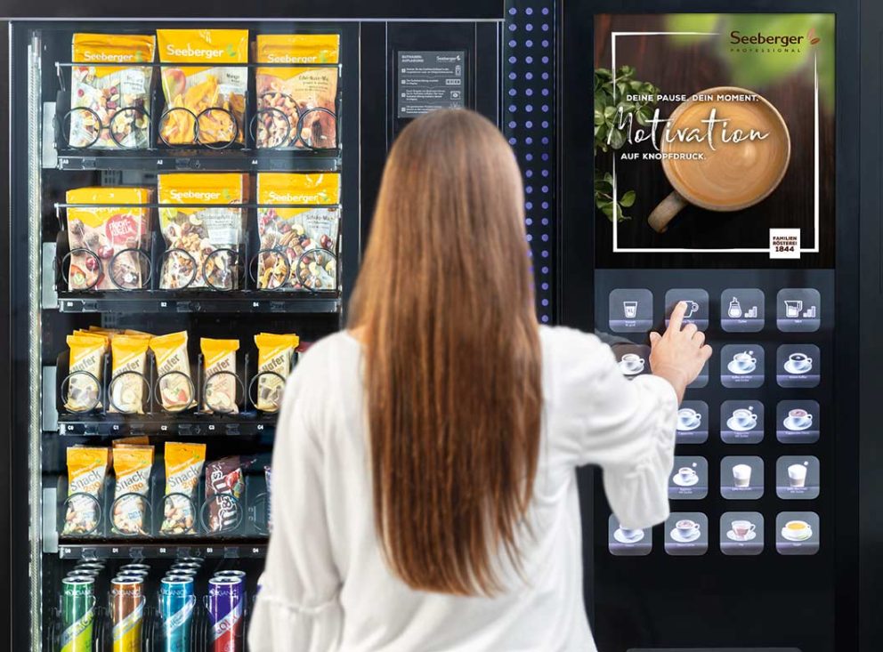 Person wählt Produkt am Vendingautomat