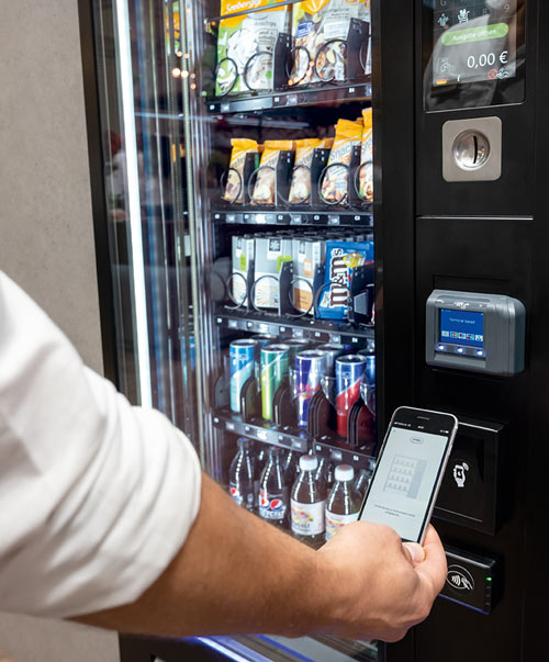 Person bezahlt mit dem Smartphone am Vendingautomat