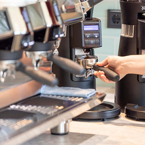 Barista mahlt frischen Kaffee an der Kaffeemühle