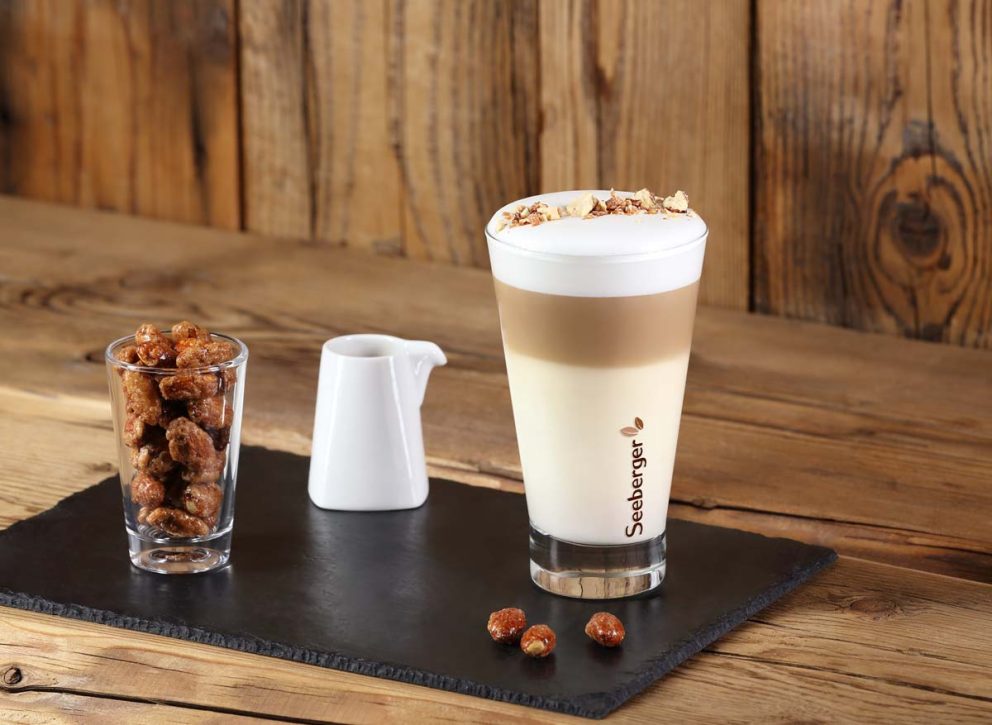 Latte macchiato mit Gebrannte Mandel-Topping und Schale mit gebrannten Mandeln