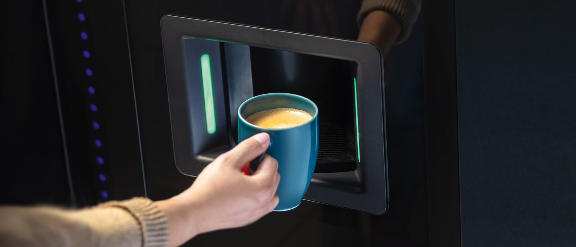 Person nimmt Kaffee aus dem Vendingautomat