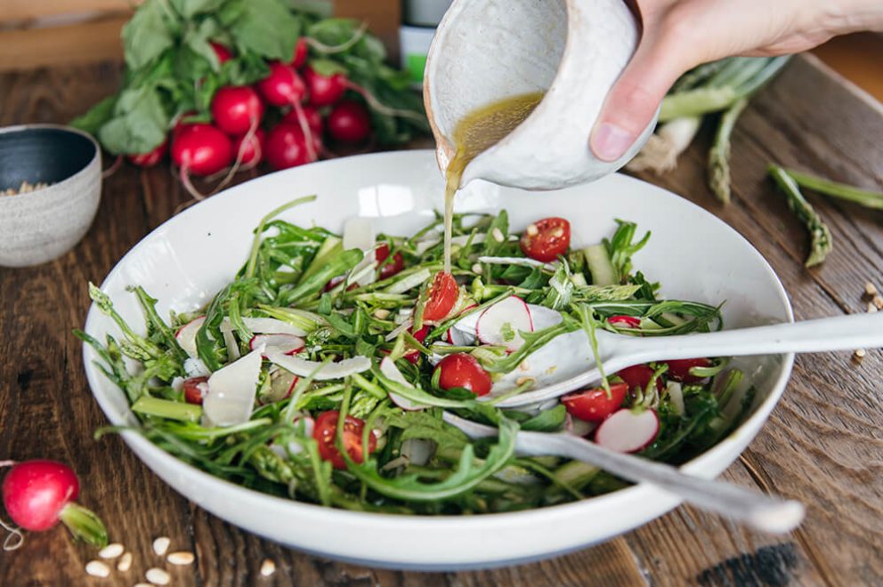 Dressing wird über Spargelsalat gegeben